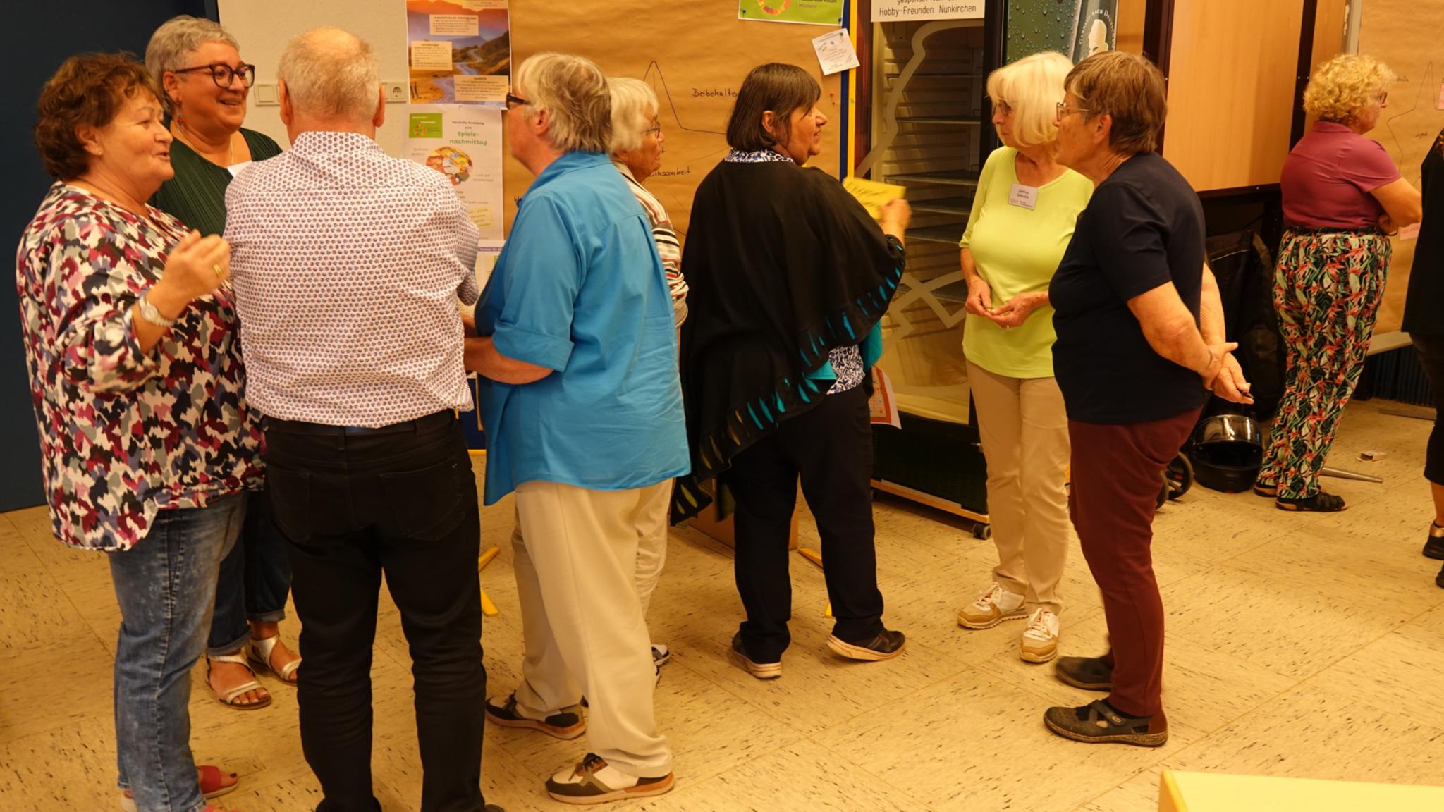 Menschen stehen vor Pinnwänden und reden miteinander_ Eindrücke aus der zweiten Synodalversammlung des Pastoralen Raumes Wadern